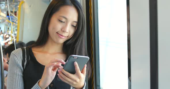 Woman use of mobile phone on train in Hong Kong