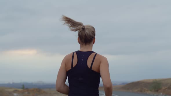 Woman Performs Cardio Training While Jogging Outdoors Background Cloudy Sky Back View