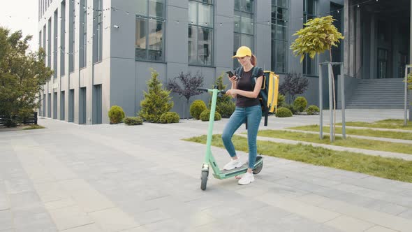 Woman Courier Food Delivery Standing with Electric Scooter and Thermal Backpack