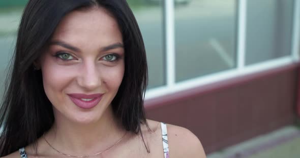 Enigmatic Brunette Corrects Her Hair and Smiles at Camera on Street