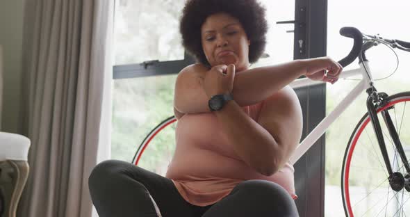 Video of midsection of plus size african american woman in sport clothes stretching at home