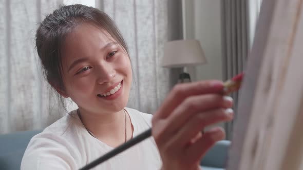 Close Up Of Asian Artist Girl Sitting And Holding Paintbrush Painting On The Canvas