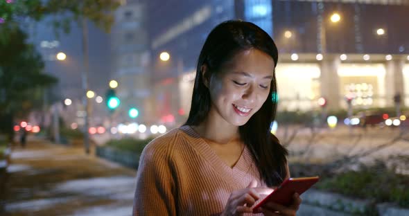 Woman look at mobile phone in city at night