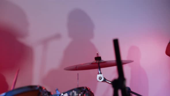 Beating Drumsticks with Multicolored Shadow Silhouettes of Musicians in Hall