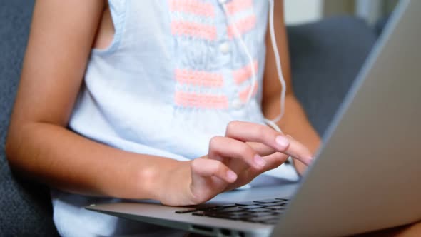 Girl with headphones using laptop in living room