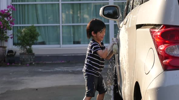 Asian Child Washing Car In The Garden On Summer Day Slow Motion