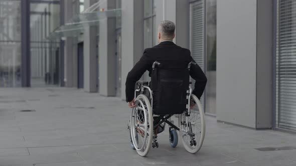 Backside View of Male Person in Suit Going on Wheel Chair at Street