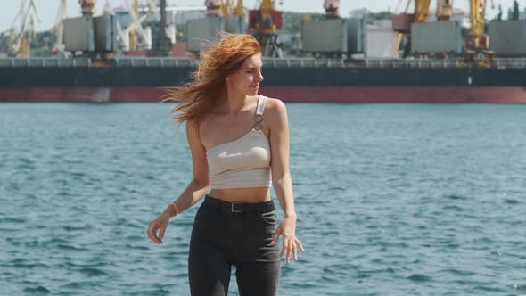 Young Stylish Funky Red Haired Girl Dancing Near Sea Port During Sunny Day