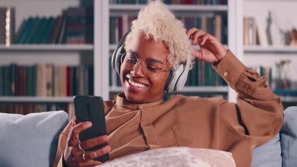 Dark Skinned Woman Sit on Sofa Wear Headphones Talk to Boyfriend By Video Call