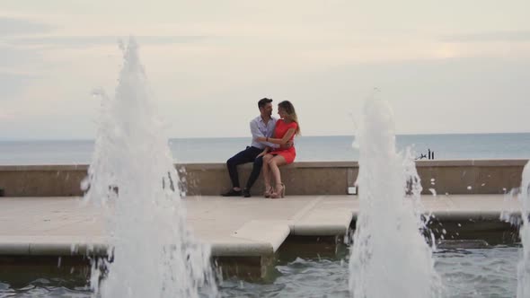 Slow motion shot of couple sitting at fountain