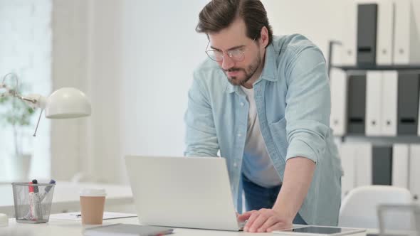 Young Man Standing and Working on Laptop