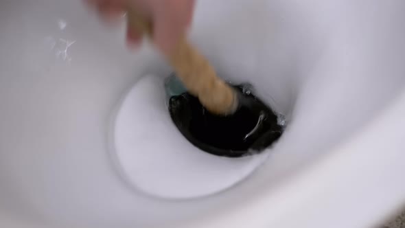 Male Hand Cleans Toilet with Plunger of Hand Pump