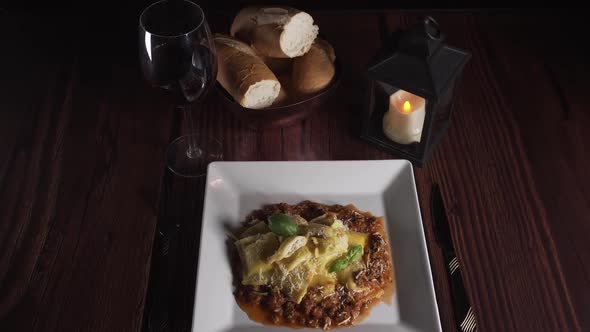 closeup to plate of pasta with sauce on a table set with cutlery and candle