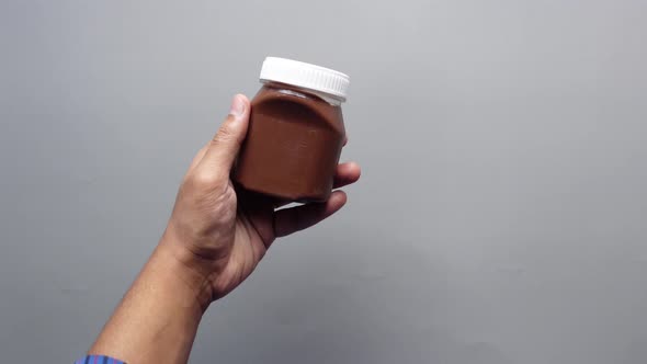 Hand Hold Chocolate Hazelnut Cream in a Container on Table