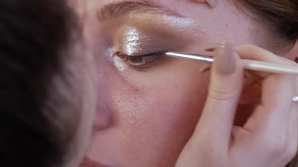 Beautiful Shiny Shadows and Eyeliner are Applied with a Special Brush on the Eyelid of the Model