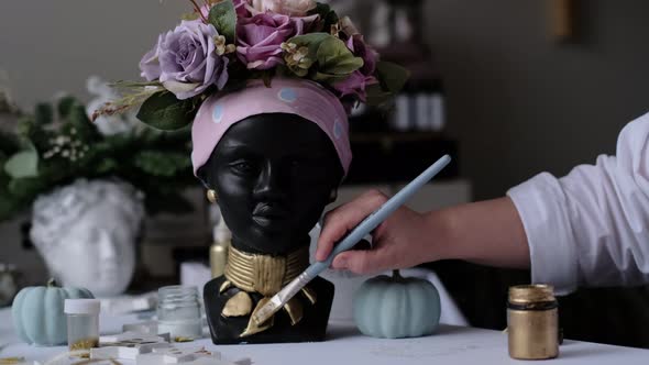 Woman Decorates a Vase in the Form of a Plaster Bust