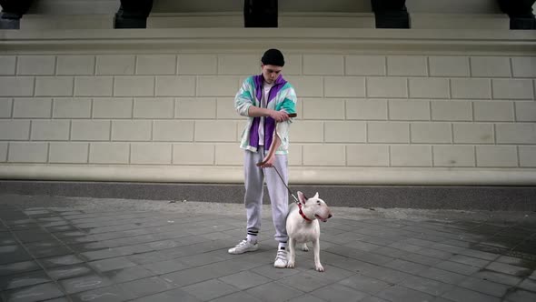 Portrait of Dangerous Man in Sporty Clothing Holding His Purebred Bullterrier Dog on Leash While