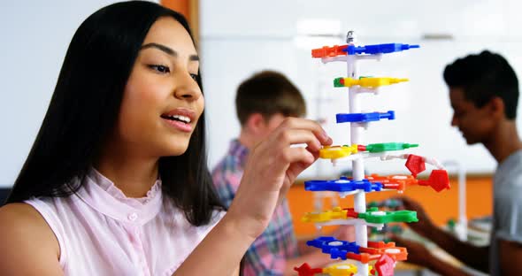 Schoolgirl experimenting molecule model in laboratory at school