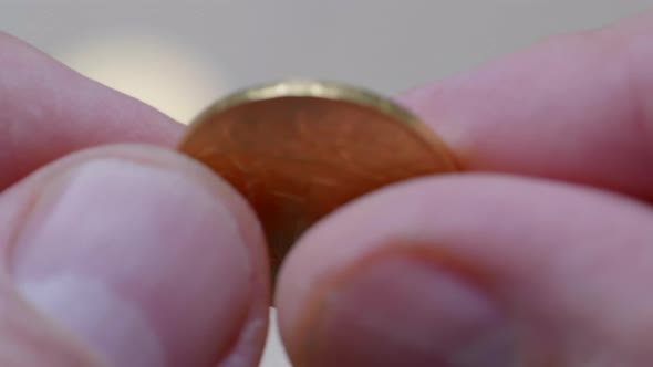 Macro shot of male finger holding swiss golden twenty franc coin with Helvetia and Swiss Cross.