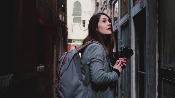 Attractive Happy Professional Journalist Woman Walking with Camera in Ancient Venice Street, Taking