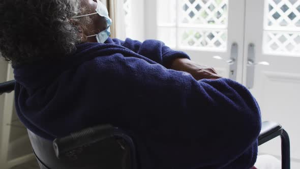 Senior african american woman wearing face mask sitting on the wheelchair at home