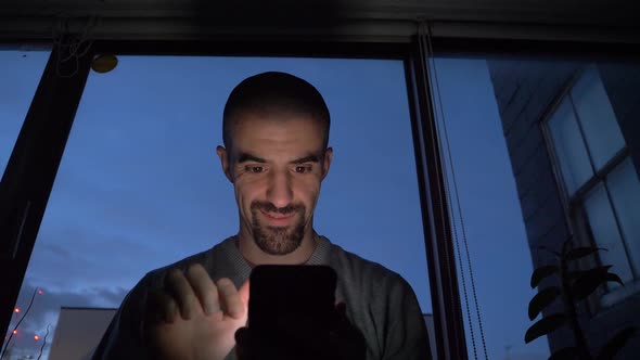 Young man using smartphone at home in the evening