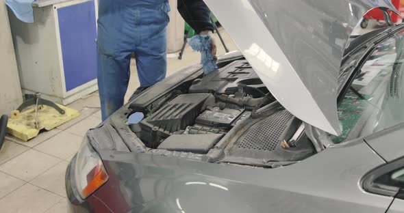 Car Mechanic Checks The Oil Level In A Car With A Dipstick