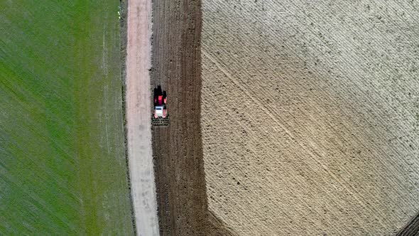 Aerial view of red tractor plowing a spring field in Poland