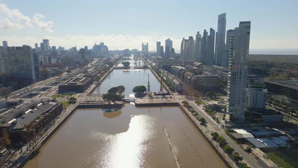 Aerial view flying over Puerto Madero's waterway with some skycrapers at right. Dolly in