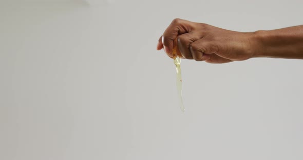 Video of hands of biracial man cracking egg on white background