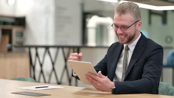 Excited Businessman Celebrating Success on Tablet in Office