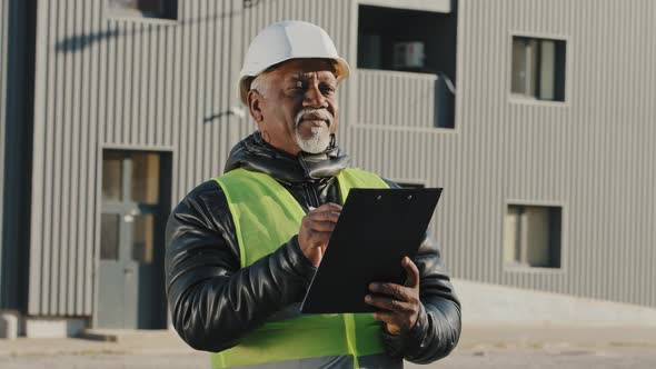 Elderly African American Man Construction Manager Evaluates Building Old Foreman Standing on Street