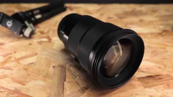 Close up Of Camera Lens With Tripod On Wooden Table.