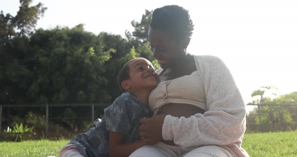 African pregnant mother and son having tender moment at city park