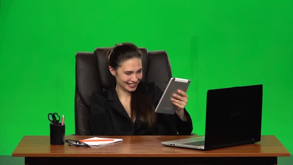 Worker Girl Sits at a Workplace Leaning Back in a Leather Chair and Communicates on a Tablet, Very