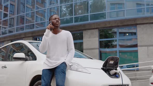 Stylish African American Man in the Yard of a Residential Complex Talking on a Cell Phone Leaning on