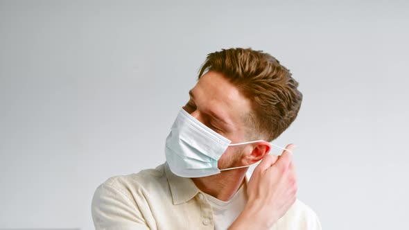 Experienced male model with beard takes off blue disposable face mask