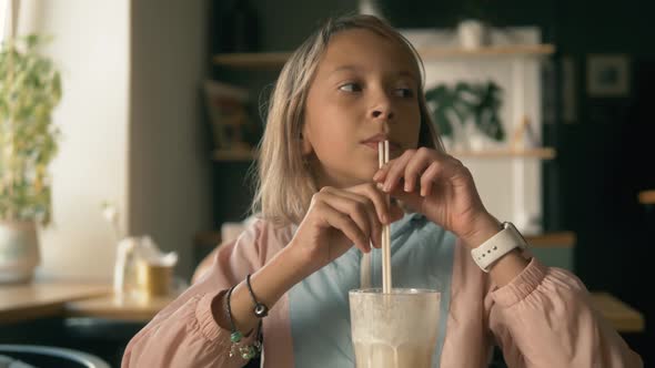 Beautiful Girl in Sitting in Cafe Counter and Drinking Milkshake While Taking Cute Photos