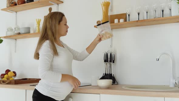 Pregnant Woman in the Kitchen Prepares a Quick Nutritious Breakfast of Cereals