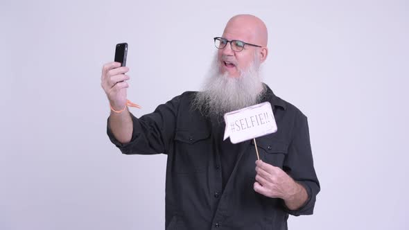 Happy Mature Bald Bearded Man Taking Selfie with Paper Sign