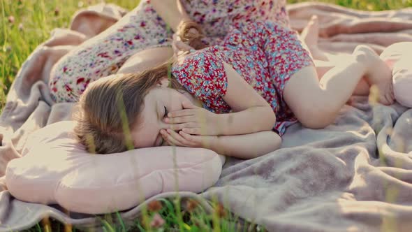 Young Mother in a Summer Dress Gently Strokes the Hair of a Cute Daughter