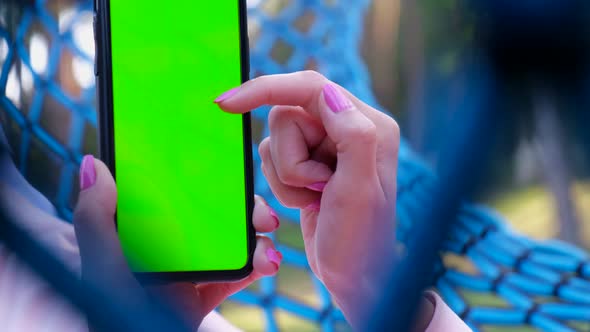 Girl holding a smartphone with a chroma key screen