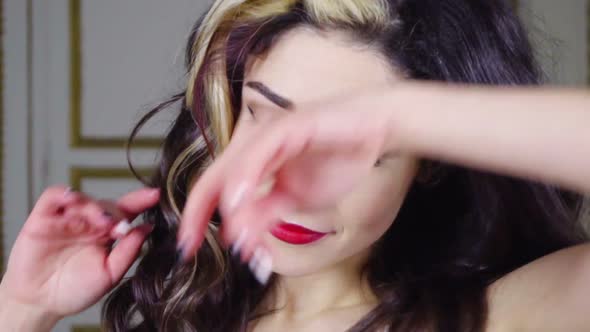 Young Brunette Woman with Red Lip Looks at Camera