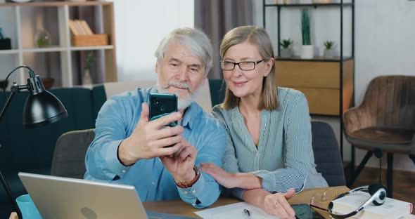 Smiling Mature Couple Using Smartphone for Taking Selfie