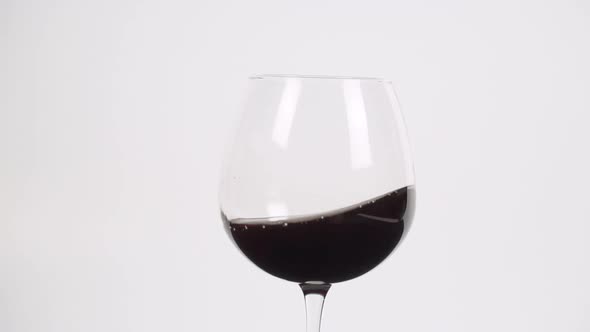Swirling red wine in burgundy glass