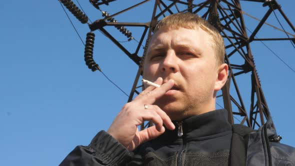 Portrait of Adult Serious Man Looking Into Camera and Smoking Cigarette Outdoor