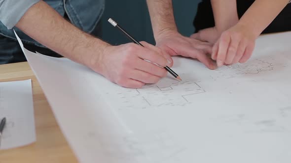 Close Up Hands of Two Workers Discussing Building Drawings in Office. Closeup Shooting of Arms
