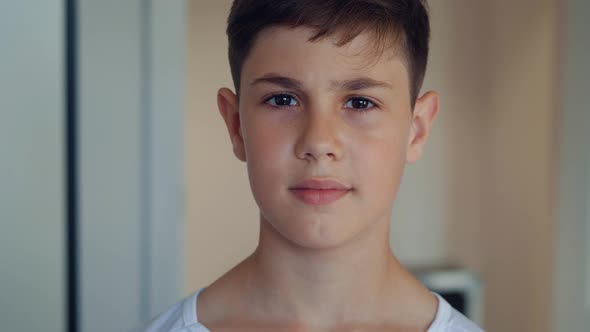 Portrait of Handsome Boy of 12 Ages in White Shirt Looking at Camera at Home