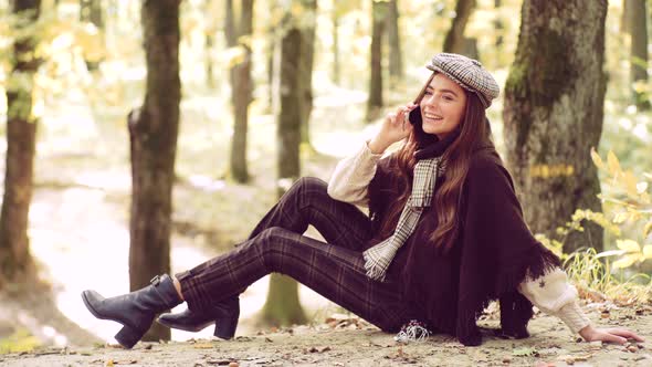 Autumn Woman. Happy Woman Using Smart Phone. Social Media Phone. Beautiful Young Brunette Sitting on