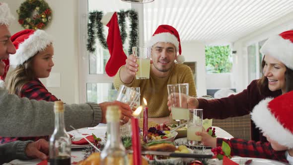 Happy caucasian multi generation family wearing santa hats, having christmas meal